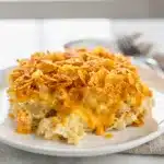 Creamy crockpot hashbrown casserole with crispy cornflake topping in ceramic dish.