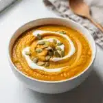 Creamy butternut squash soup garnished with coconut cream and pumpkin seeds