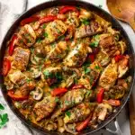 Creamy skillet chicken dinner with bell peppers and mushrooms on rustic table