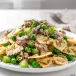 Creamy tuna pasta salad with bowtie pasta peas and celery in white bowl