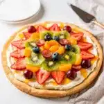 Colorful fruit pizza with creamy frosting on a sugar cookie crust overhead view