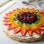 Bakery style fruit pizza sugar cookie with creamy frosting and fresh fruit.