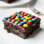 Fudgy cosmic brownies with glossy ganache and colorful candy sprinkles close up.