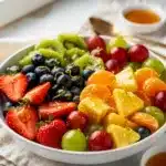 Colorful honey lime fruit salad with fresh berries and citrus on wood