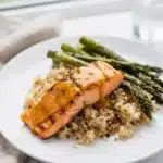 Honey mustard salmon fillets with dill garnish on a white plate.