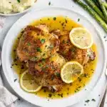 Crispy lemon garlic chicken thighs with a glossy pan sauce and fresh herbs.