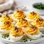 Make ahead deviled eggs with creamy filling and paprika garnish on wood.
