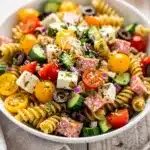 Colorful make ahead pasta salad with mozzarella salami and fresh vegetables.