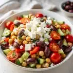 Vibrant Mediterranean chickpea salad with fresh vegetables and feta in a rustic bowl.