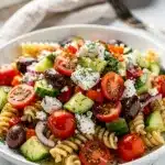 Colorful Mediterranean pasta salad with fusilli, feta, olives, and fresh vegetables in a lemon vinaigrette.