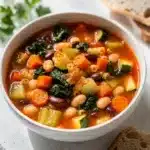 Rustic minestrone soup with pasta beans and vegetables in tomato broth