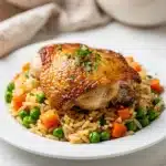 Golden one pot chicken and rice with peas carrots and fresh parsley garnish