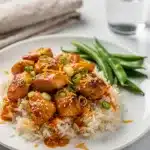 Orange chicken skillet recipe in cast iron pan with glossy sauce and garnishes