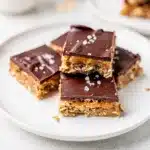 Perfect peanut butter chocolate bars with fudgy topping and oat base on marble counter.