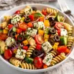 Colorful picnic pasta salad with rotini, fresh vegetables, and herb vinaigrette.