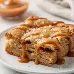Salted caramel blondies with chewy texture and glossy swirls on white plate.