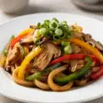 Savory udon stir fry with chicken, mushrooms, and crisp vegetables in glossy sauce.
