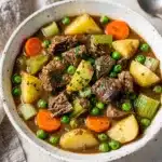 Hearty slow cooker beef stew with tender beef potatoes carrots and peas