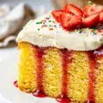 Moist yellow cake soaked with vibrant red strawberry gelatin and fluffy frosting