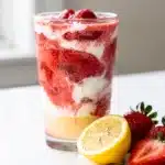 Bright strawberry lemonade smoothie in a tall clear glass with straw