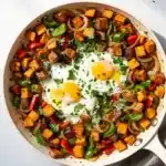Crispy sweet potato breakfast hash with eggs in a cast iron skillet.