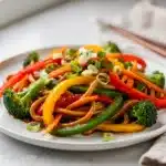 Vibrant fast udon stir fry with vegetables in a ceramic bowl.