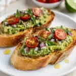 Avocado bruschetta recipe on toasted baguette with fresh tomato and herbs