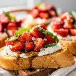 Creamy ricotta bruschetta topped with fresh strawberries and glossy balsamic syrup