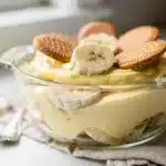 Layered banana pudding trifle in glass bowl with vanilla wafers and creamy custard.