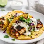 Blackened fish tacos with creamy lime slaw on wood.