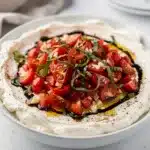 Creamy bruschetta dip with fresh tomatoes and basil on toasted bread.