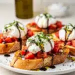 Creamy burrata bruschetta with heirloom tomatoes and fresh basil on toasted baguette.