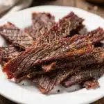Classic homemade beef jerky recipe with savory marinade on rustic wooden board.