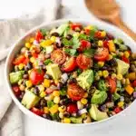 Cowboy caviar dip with avocado and beans in a rustic ceramic bowl