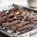 Easy homemade beef jerky recipe with savory marinade on rustic cutting board.