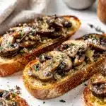 Creamy garlic mushrooms on crispy toasted bruschetta appetizer close up food photo