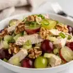 Creamy grape walnut chicken salad in a white bowl on rustic wood