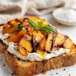 Grilled peach and ricotta toast on crispy bread with honey drizzle