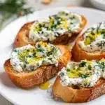 Herbed goat cheese crostini with honey and fresh herbs on rustic bread