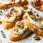 Honey goat cheese bruschetta with toasted bread and fresh herbs close up