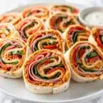 Italian Pinwheel Sandwiches with pesto, meats, cheese, and spinach in cross-section.