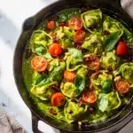 Creamy Pesto Tortellini Skillet with cherry tomatoes and basil.