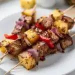 Juicy pineapple BBQ pork skewers with caramelized glaze and char marks.