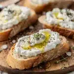 Creamy ricotta honey bruschetta on rustic toasted bread with thyme garnish