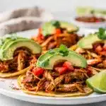 Shredded chicken tacos with cilantro, onion, and cotija cheese.