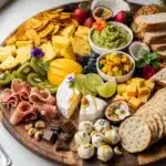 Colorful tropical fruit grazing board with brie and prosciutto for summer entertaining