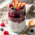 Creamy layered chia pudding with mixed berry compote in jar