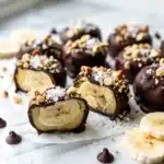 Vibrant frozen banana bites with glossy dark chocolate coating